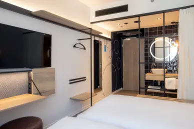 Hotelzimmer mit Blick auf das offene, blaue Bad. Das Bad wird abgetrennt durch einen Vorhang. Hotelzimmer mit Blick auf das offene, blaue Bad. Das Bad wird abgetrennt durch einen Vorhang.